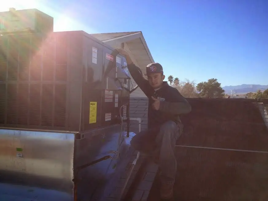 HVAC technician performing AC Tune-Up on a rooftop unit in Coalinga