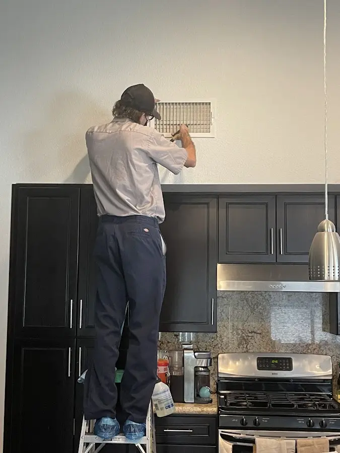 Technician inspecting an air vent during HVAC service in Coalinga